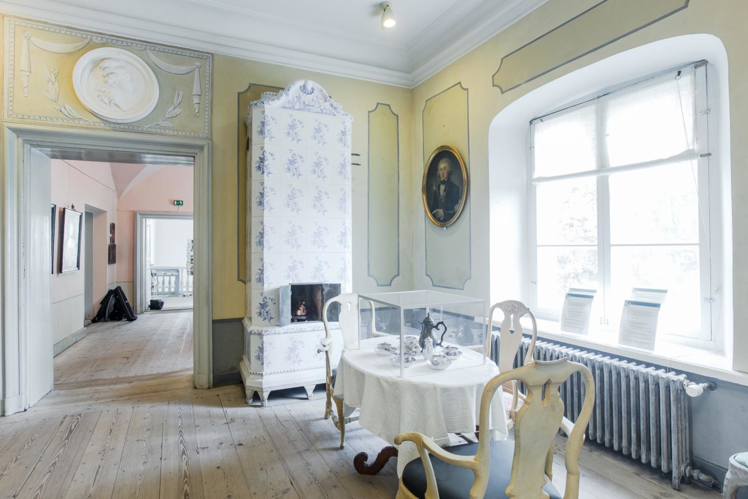 1700-luvun rokokoo tyyliin sisustettu huone, jossa katettu kahvipöytä. Kahvipöydän takana kaakeliuuni sekä ikkuna.