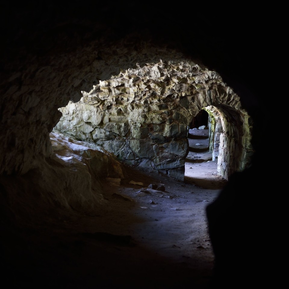 Kolvikaarinen tunneli, jonka sivuaukoista lankeaa valoa maahan.